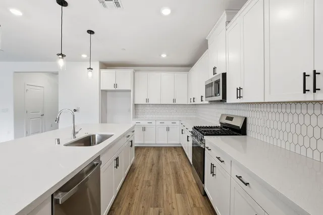 a kitchen with granite countertop a sink a counter space stainless steel appliances and cabinets