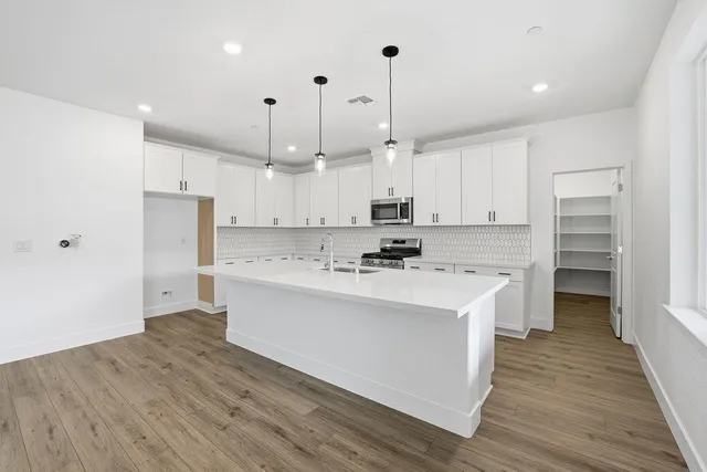 a kitchen with kitchen island a sink a stove a refrigerator and white cabinets