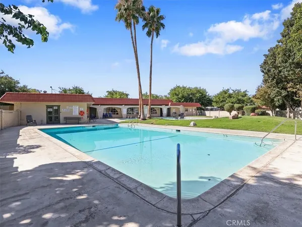 a view of swimming pool with a yard and palm trees