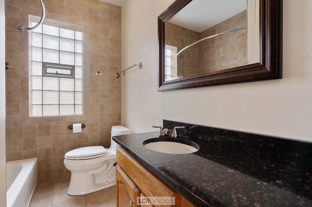 7112 West Belden Avenue Chicago, IL 60707 - Photo 11 of 19 a bathroom with a sink toilet a mirror and a window