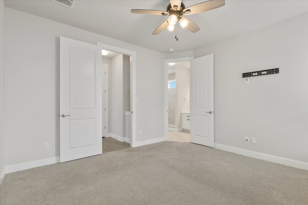 101 Free Stone Drive Georgetown, TX 78628 - Photo 13 of 40 Carpeted room featuring a ceiling fan with integrated lighting, two white panel doors, and neutral wall tones