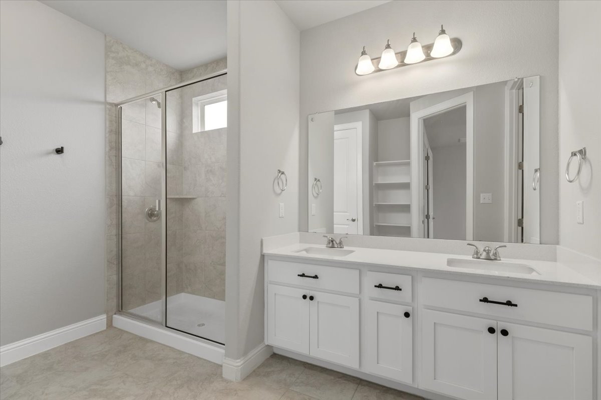 101 Free Stone Drive Georgetown, TX 78628 - Photo 14 of 40 Modern bathroom featuring a double vanity with white cabinetry, integrated sinks, and a full-width mirror