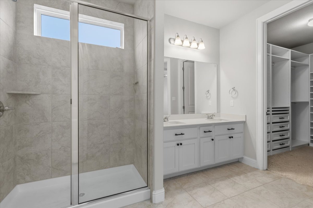 101 Free Stone Drive Georgetown, TX 78628 - Photo 15 of 40 Full bathroom featuring a tiled shower with transom window, glass enclosure, and built-in shelving
