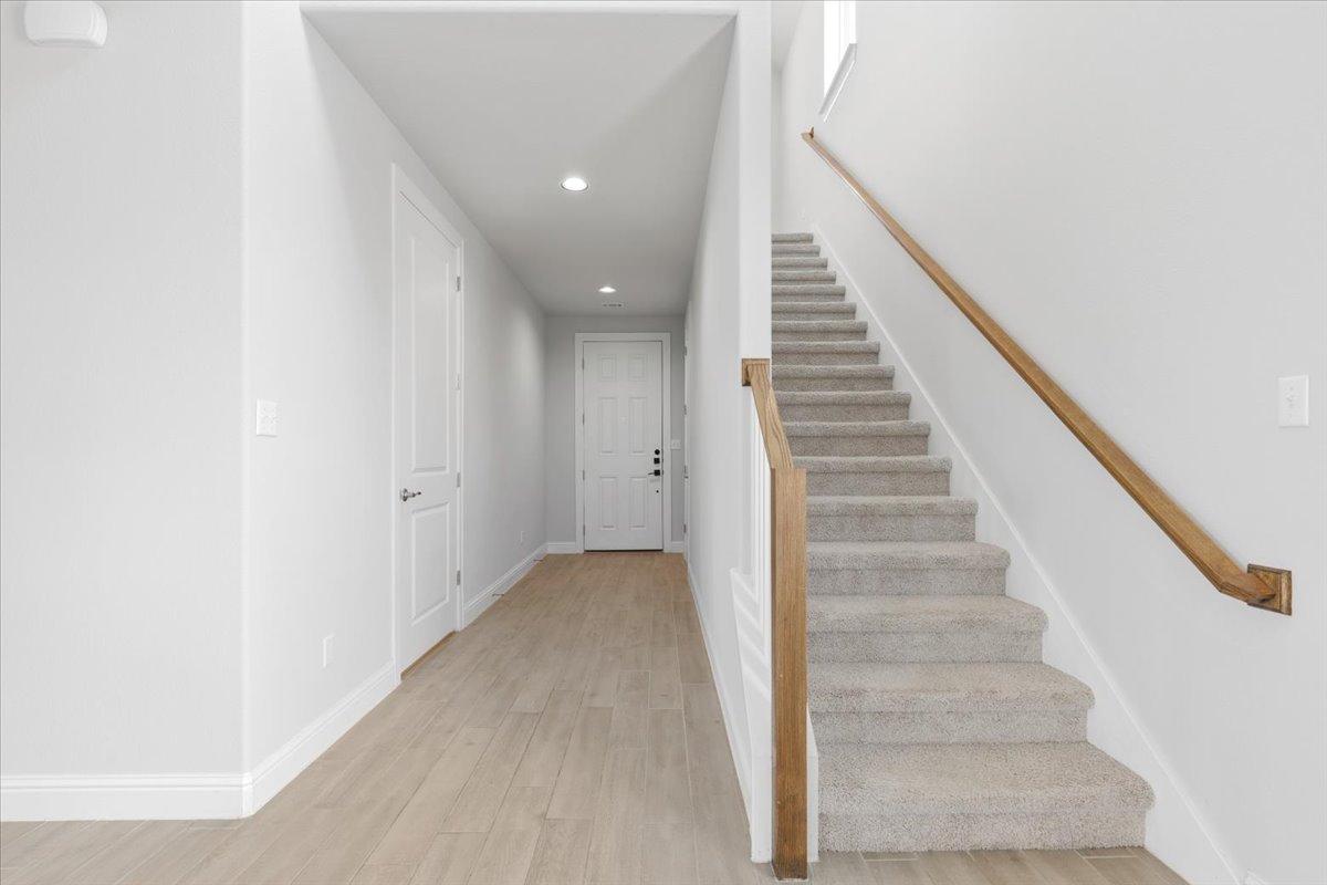 101 Free Stone Drive Georgetown, TX 78628 - Photo 18 of 40 Entryway featuring wood-finish flooring, recessed lighting, white panel doors, and a carpeted staircase with a wood handrail