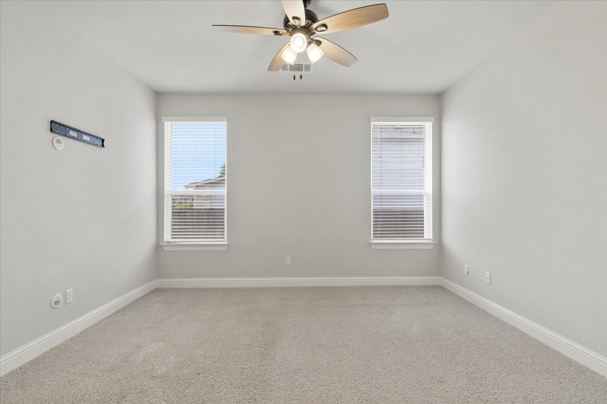 101 Free Stone Drive Georgetown, TX 78628 - Photo 22 of 40 Carpeted room with a ceiling fan light fixture, two windows with blinds, and white trim molding
