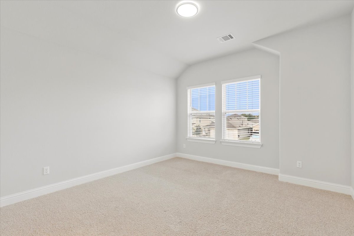 101 Free Stone Drive Georgetown, TX 78628 - Photo 26 of 40 Carpeted room featuring two windows with blinds, a vaulted ceiling, recessed lighting, and white baseboards