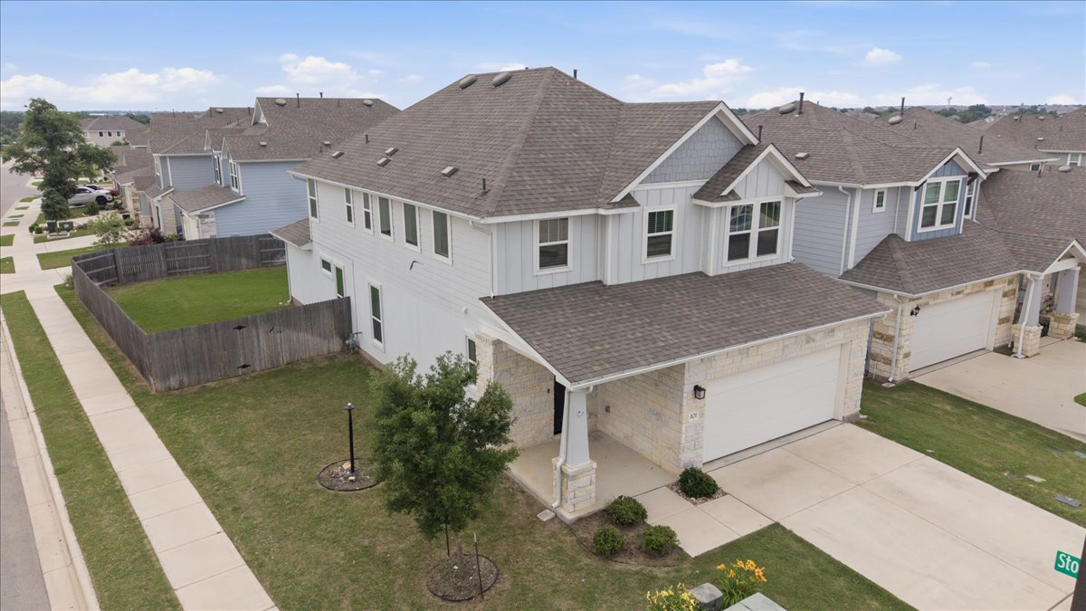 101 Free Stone Drive Georgetown, TX 78628 - Photo 34 of 40 Two-story residence featuring light gray siding, stone accents, a dark shingle roof, an attached two-car garage, and a fenced backyard with a manicured lawn