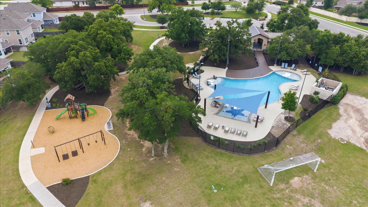 101 Free Stone Drive Georgetown, TX 78628 - Photo 37 of 40 Expansive outdoor amenity area featuring a large swimming pool with shade structures, a fenced playground with swings and a slide, an adjacent soccer goal, and mature trees throughout