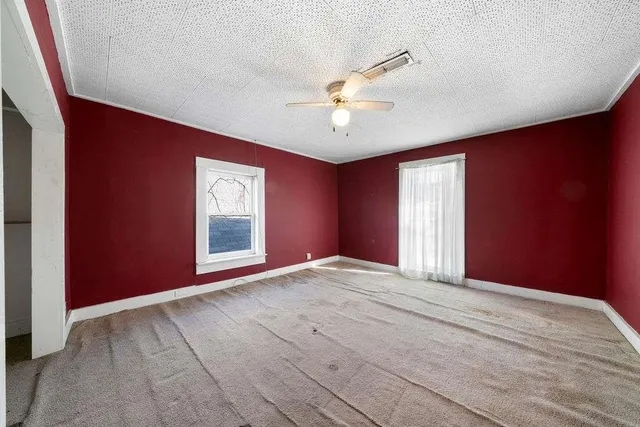 an empty room with windows and chandelier fan