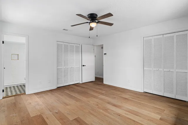 an empty room with fan and windows