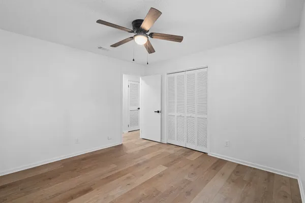 a view of a room with wooden floor and ceiling fan