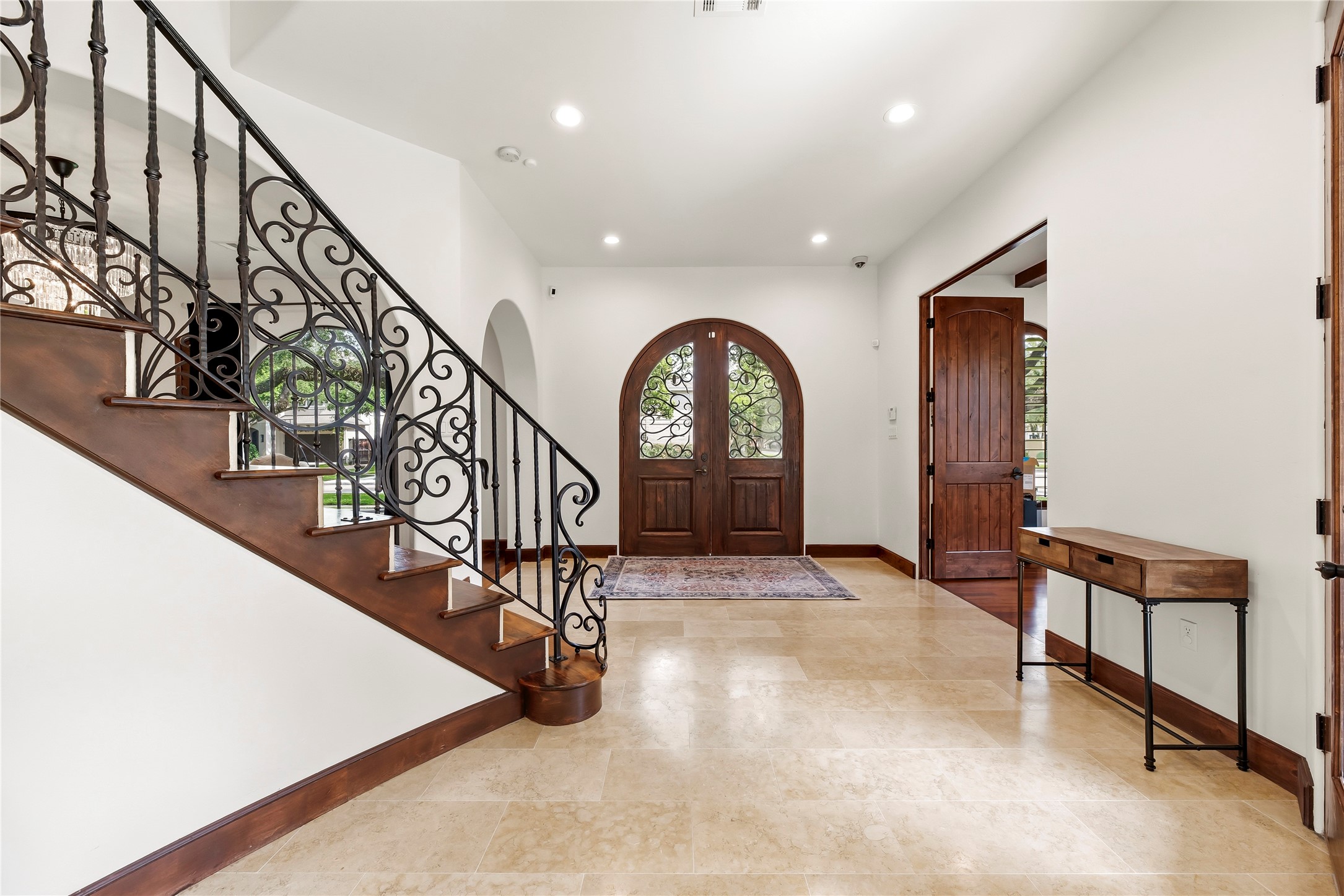 3803 Drake Street Houston, TX 77005 - Photo 4 of 32 Stunning arched wood double doors open to a soaring foyer featuring travertine flooring and a custom wrought-iron staircase, setting a tone of timeless luxury from the moment you arrive.