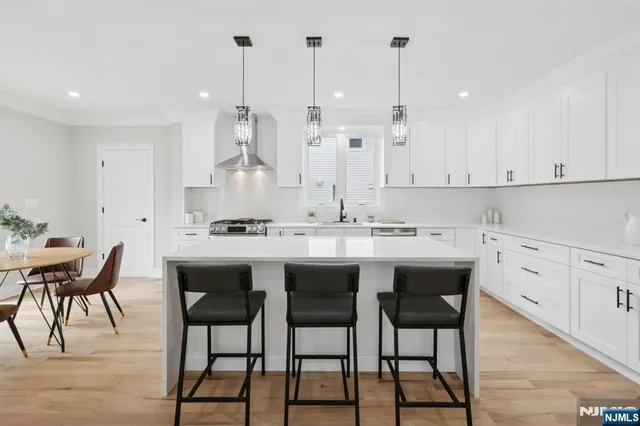 a kitchen with stainless steel appliances kitchen island granite countertop a table chairs and white cabinets