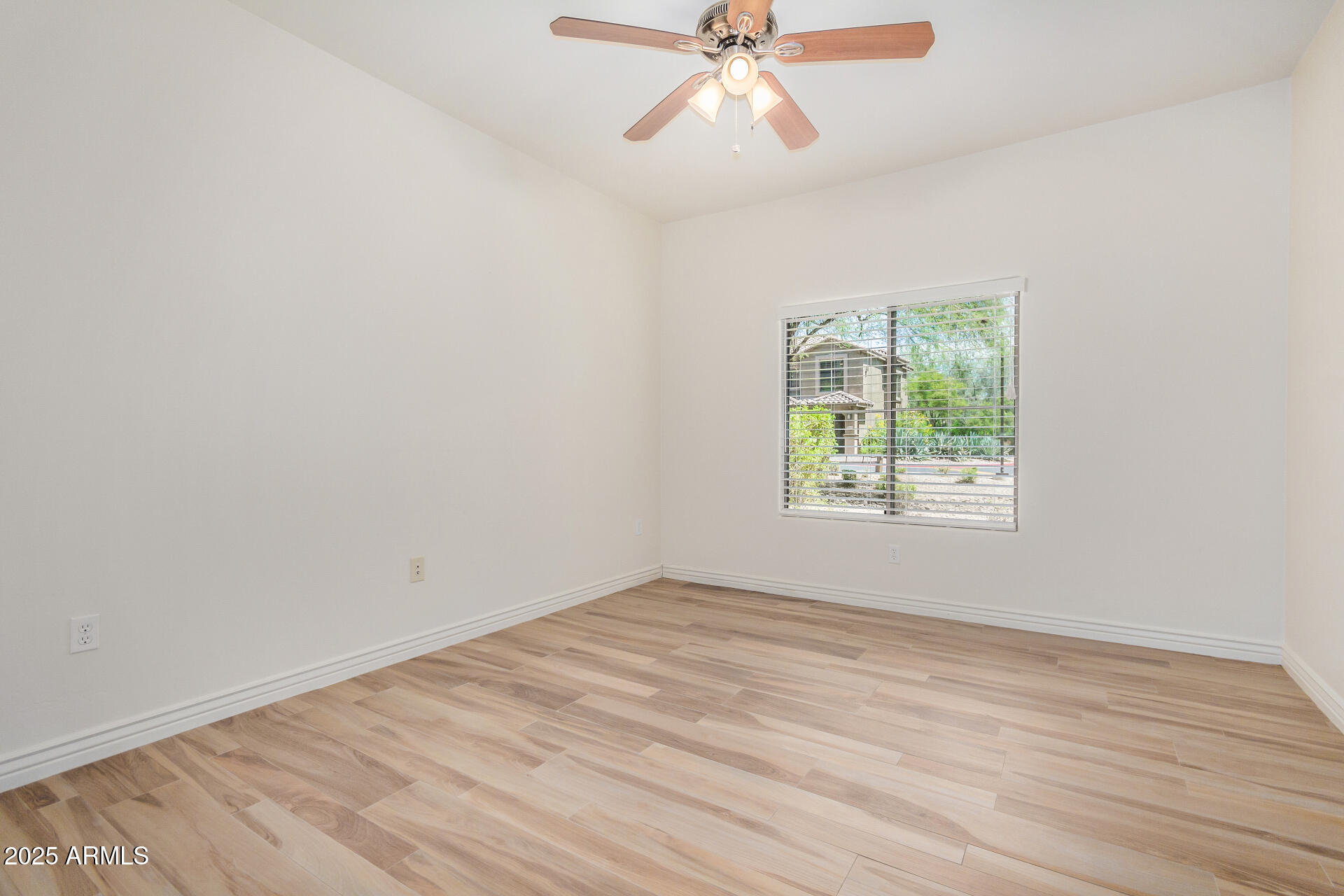 5450 East Deer Valley Drive, Unit 1211 Phoenix, AZ 85054 - Photo 11 of 26 an empty room with wooden floor fan and windows
