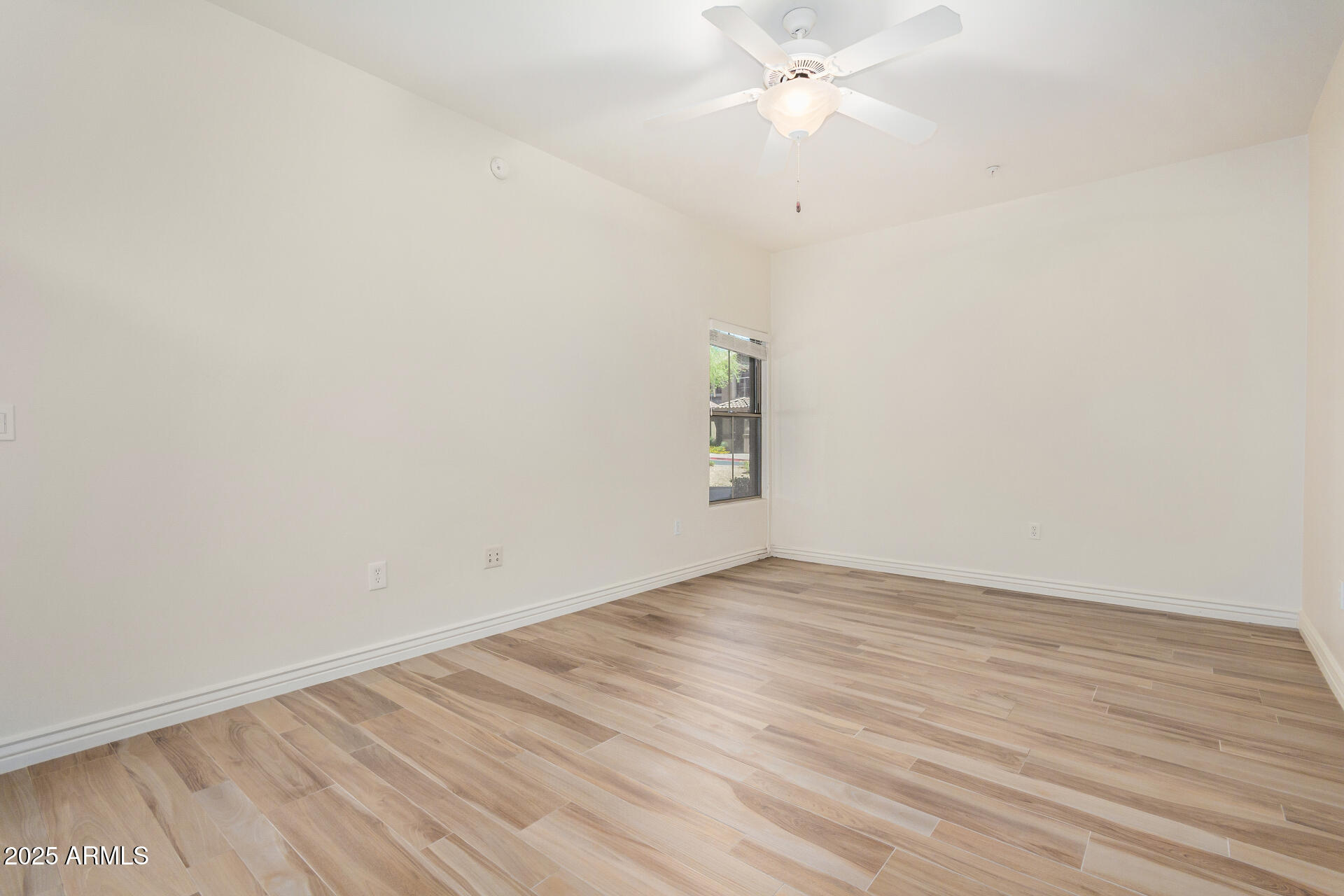 5450 East Deer Valley Drive, Unit 1211 Phoenix, AZ 85054 - Photo 19 of 26 an empty room with wooden floor and fan