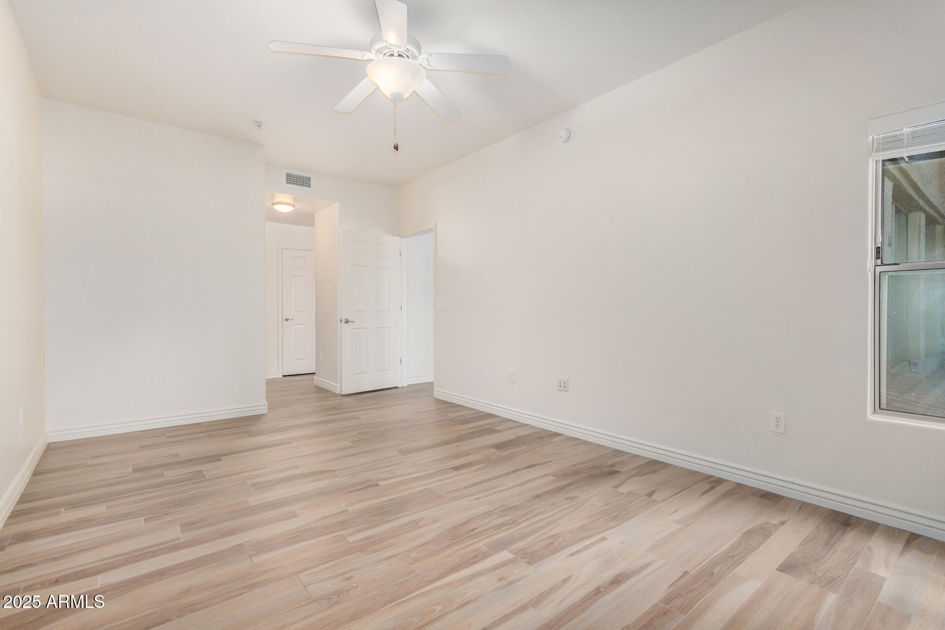 5450 East Deer Valley Drive, Unit 1211 Phoenix, AZ 85054 - Photo 20 of 26 an empty room with wooden floor and ceiling fan