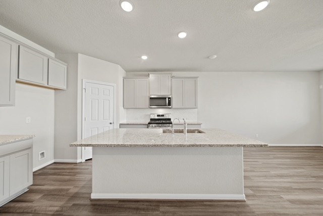 10422 Sherwin Pass Drive Rosharon, TX 77583 - Photo 7 of 26 a large white kitchen with granite countertop a stove a sink and white cabinets