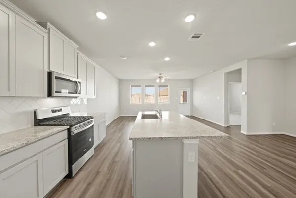 a large kitchen with granite countertop a stove top oven a sink a counter space and cabinets