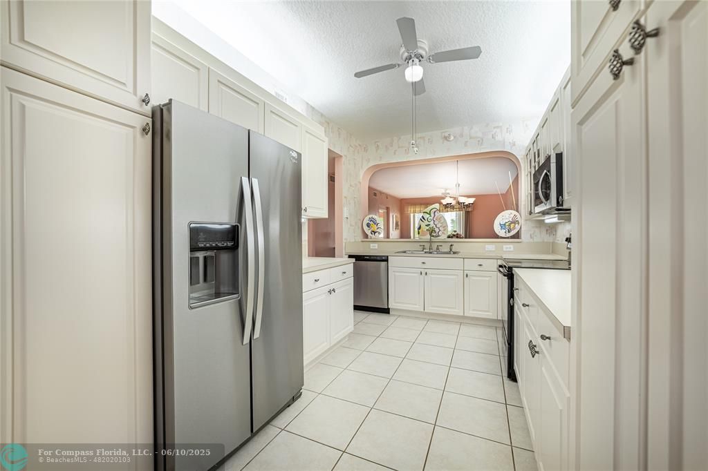7739 Southampton Terrace, Unit 202 Tamarac, FL 33321 - Photo 5 of 39 a kitchen with white cabinets stainless steel appliances and a refrigerator