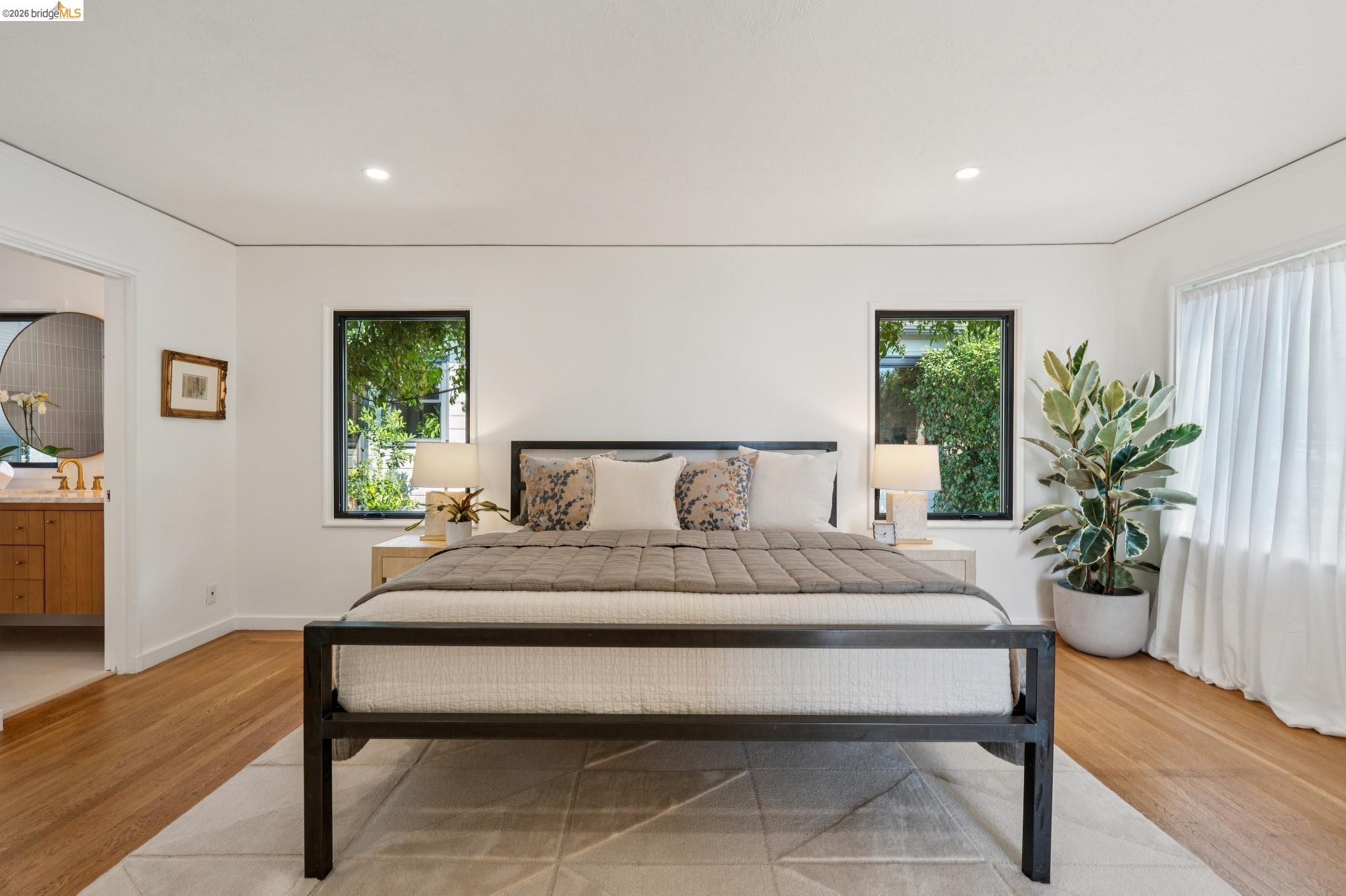 38 Highgate Road Kensington, CA 94707 - Photo 20 of 78 Light wood-finish flooring, two rectangular windows with dark frames, recessed ceiling lighting, and a white vanity with a circular mirror