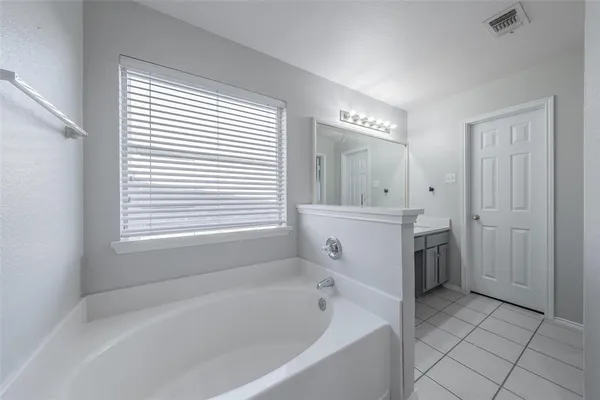 a bathroom with a bathtub a sink a vanity and a window