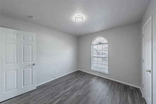 an empty room with wooden floor cabinet and windows