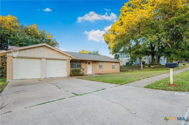a view of a house with a yard and large tree