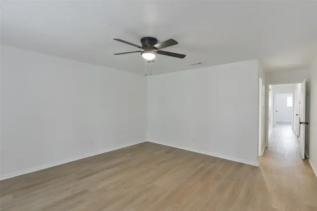 a view of a room with wooden floor and a ceiling fan