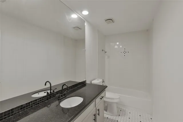 a bathroom with a granite countertop sink a toilet a mirror and bathtub