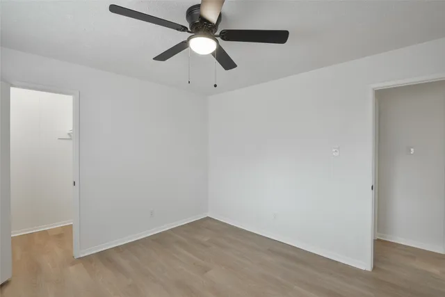 an empty room with wooden floor and ceiling fan