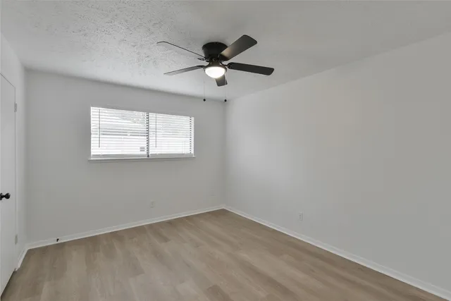 an empty room with a window and a fan