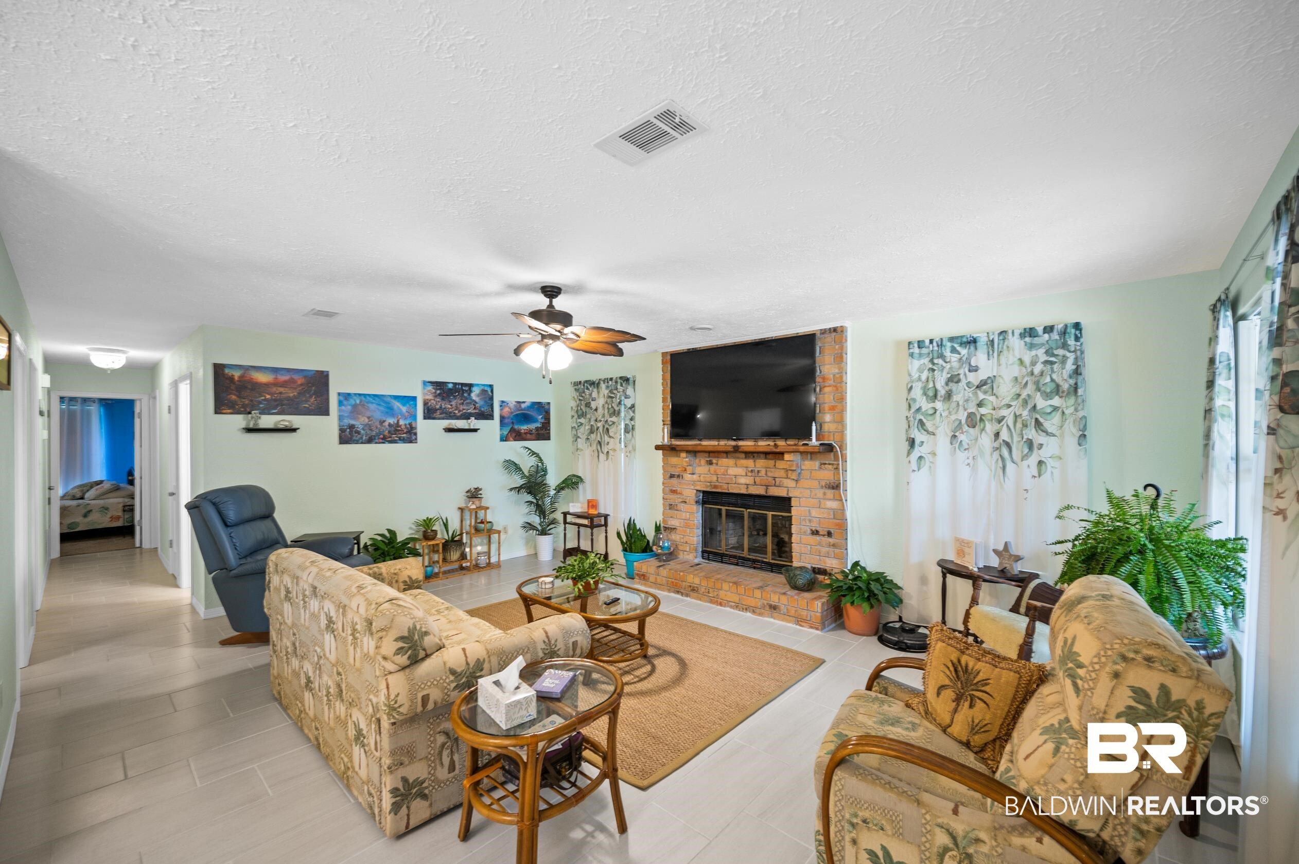 2772 Santa Rosa Circle Lillian, AL 36549 - Photo 4 of 50 Living room featuring ceiling fan, a brick fireplace, brick wall, a textured ceiling, and light tile patterned floors