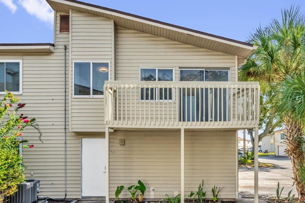 a view of a white house with large windows and flower plants