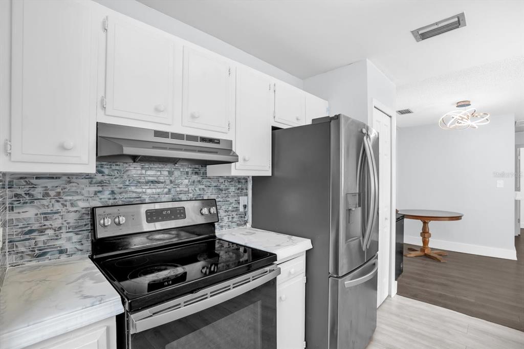 1121 Spring Meadow Drive, Unit 11221 Kissimmee, FL 34741 - Photo 11 of 28 a kitchen with granite countertop a refrigerator stove and cabinets