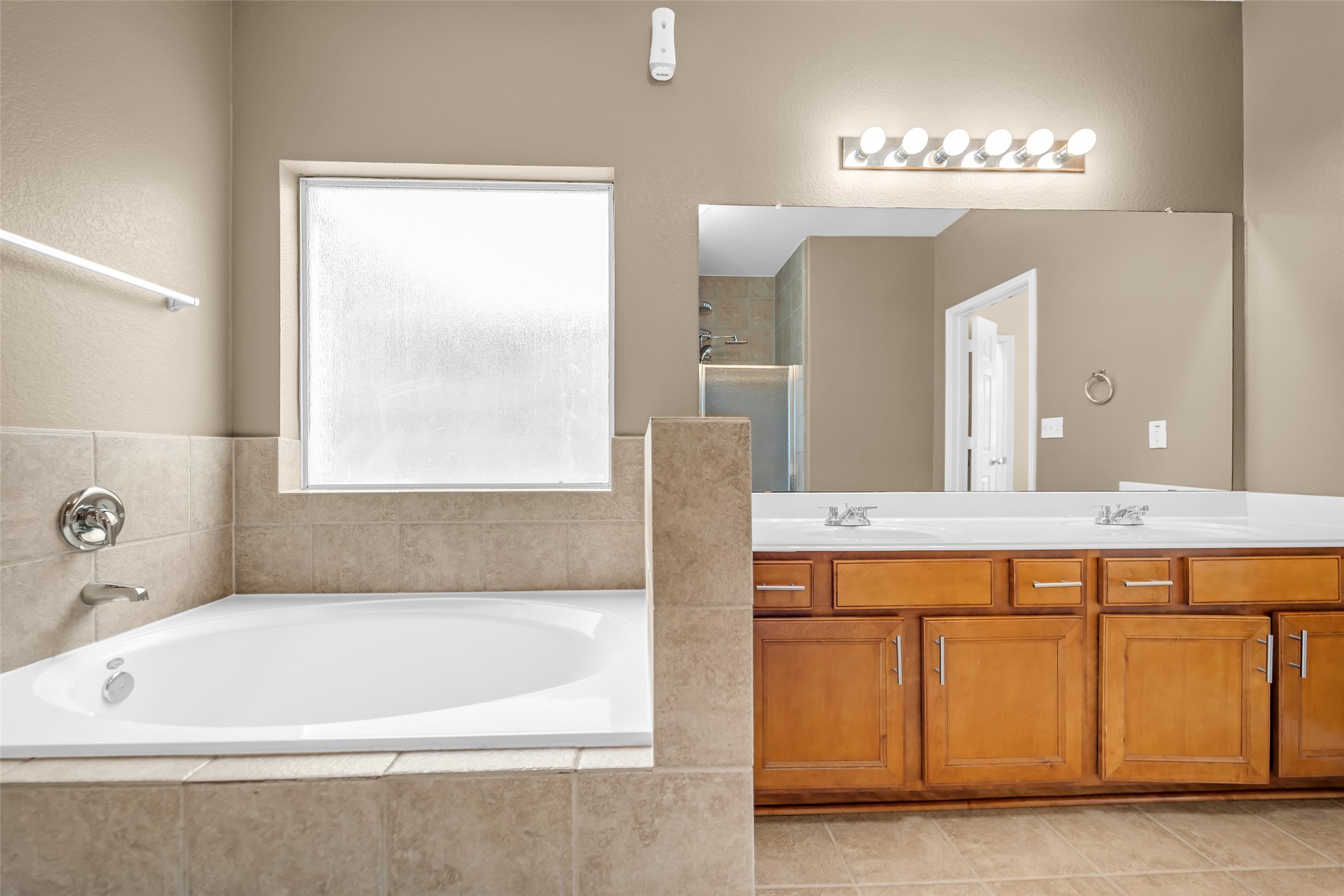 5406 Quarry Ridge Road Richmond, TX 77407 - Photo 22 of 36 Relax and recharge in the primary bath featuring a soaking tub, expansive double vanity, and a separate glass-enclosed shower visible in the mirror, creating a spacious and well-appointed owner's retreat.