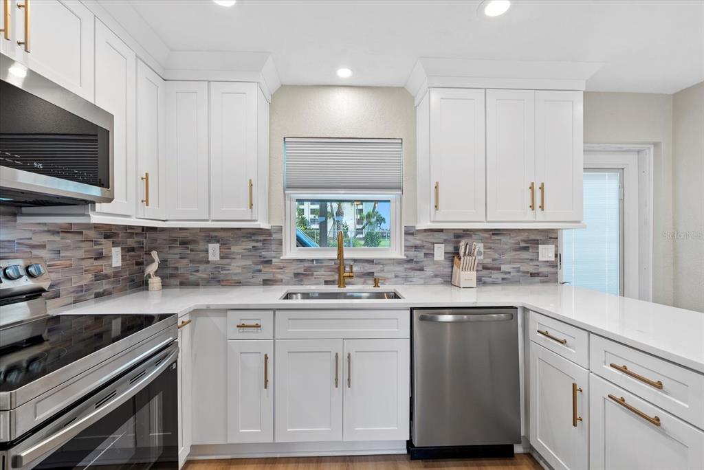 5830 Midnight Pass Road, Unit 25 Sarasota, FL 34242 - Photo 4 of 29 a kitchen with white cabinets stainless steel appliances and sink