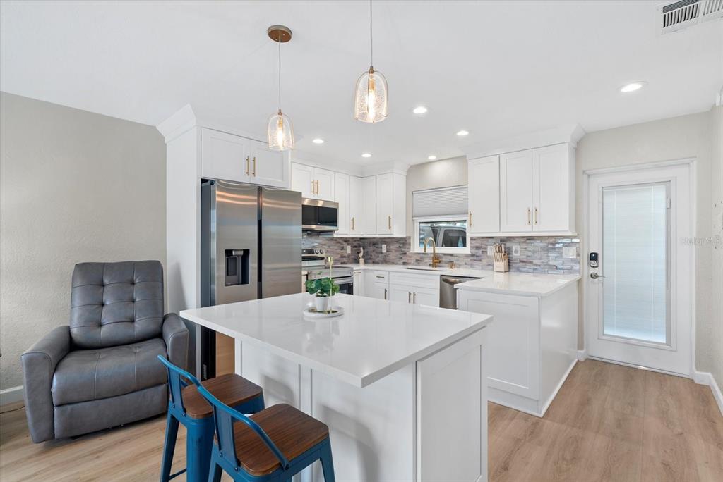 5830 Midnight Pass Road, Unit 25 Sarasota, FL 34242 - Photo 8 of 29 a kitchen with stainless steel appliances kitchen island a refrigerator and a stove top oven