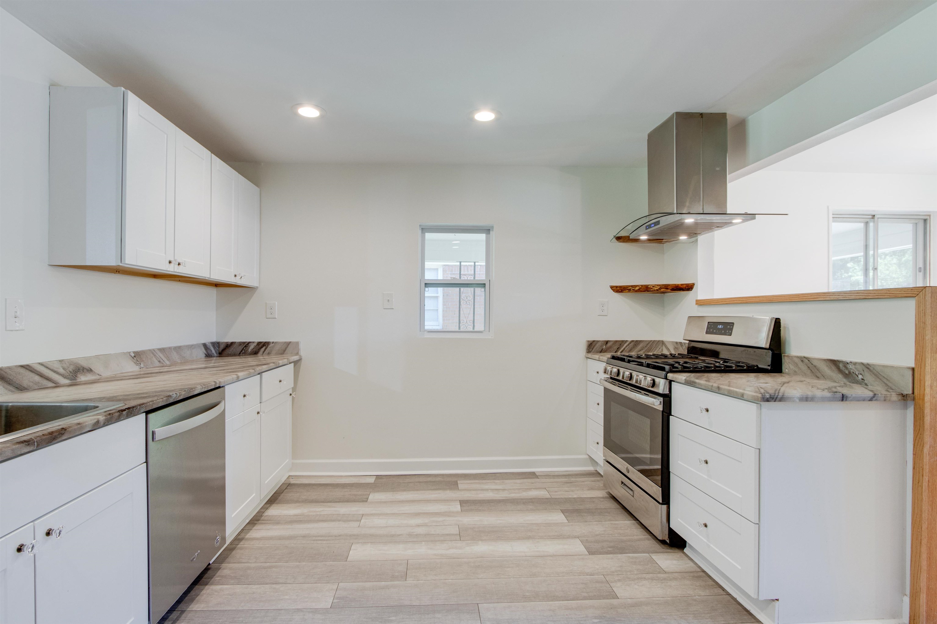 5418 Mesquite Road Memphis, TN 38120 - Photo 8 of 21 Kitchen featuring white cabinets, wall chimney exhaust hood, light stone countertops, and stainless steel appliances