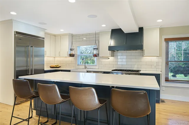a kitchen with stainless steel appliances granite countertop a stove a sink refrigerator and chairs