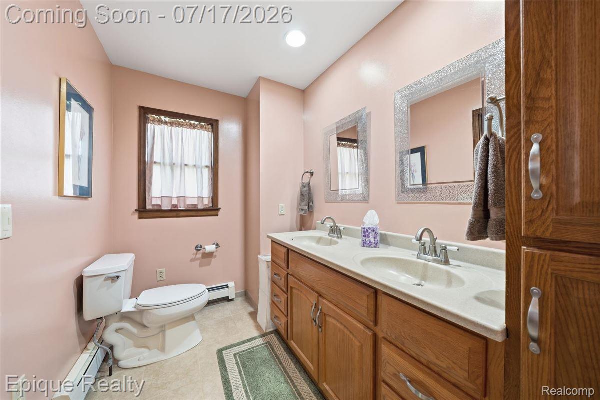 555 East Square Lake Road Troy, MI 48085 - Photo 22 of 48 Bathroom featuring a double vanity with integrated sinks, wood cabinetry, and framed mirrors