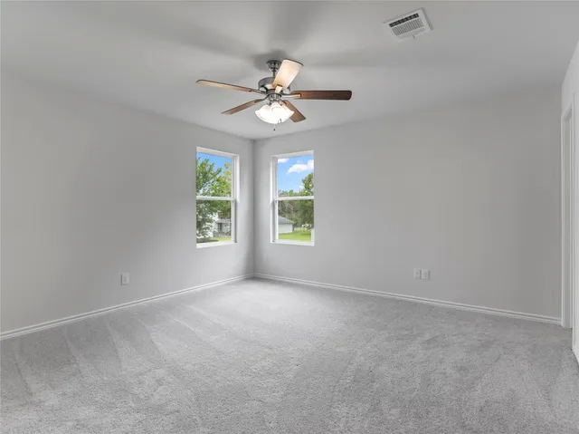 an empty room with windows and fan