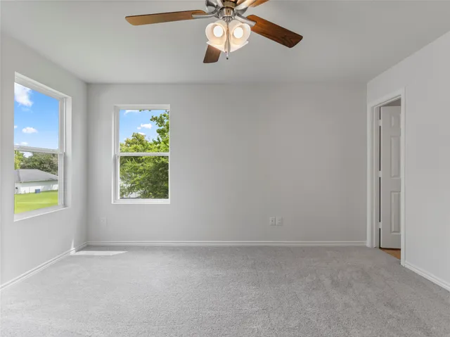 an empty room with windows and chandelier fan