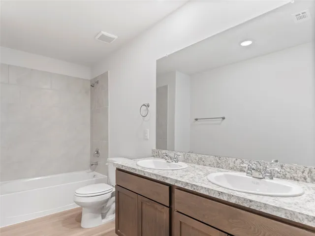 a bathroom with a granite countertop sink a toilet and a bathtub