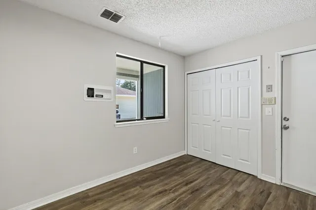 an empty room with wooden floor fireplace and windows