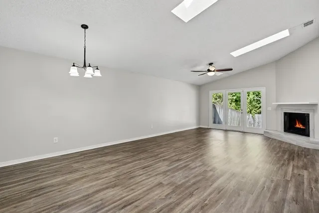 a view of an empty room with a fireplace and wooden floor