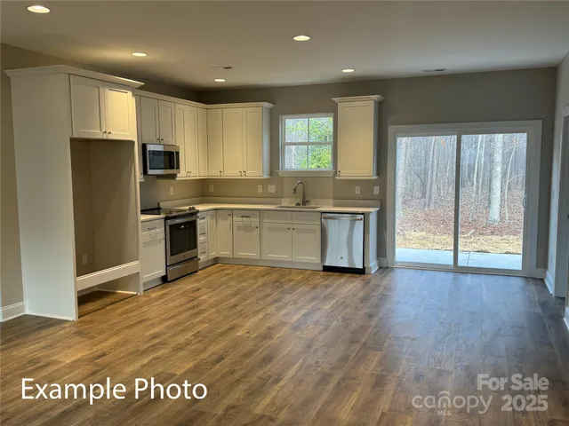 a large kitchen with kitchen island granite countertop a large window and stainless steel appliances