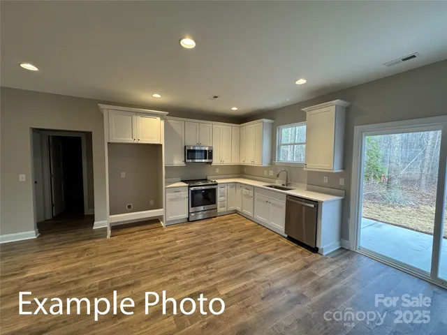 a view of a kitchen with a sink wooden cabinets and a window