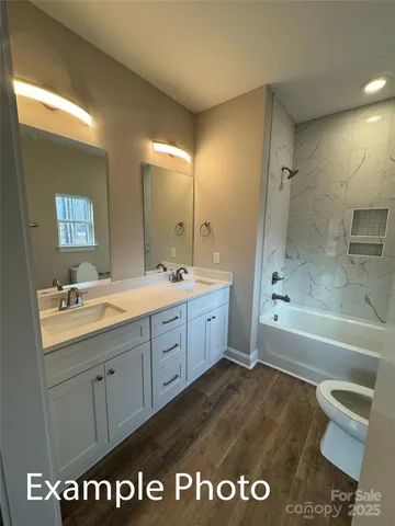 a spacious bathroom with a granite countertop sink a toilet a mirror and bathtub