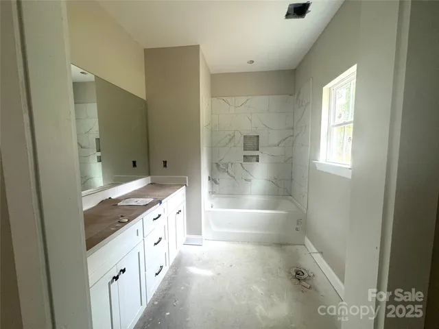 a spacious bathroom with a tub sink and mirror