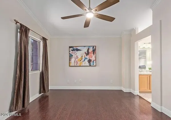 an empty room with wooden floor closet ceiling fan and windows